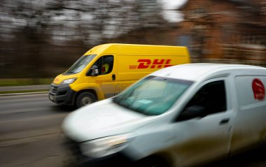 Bükreş, Romanya - 16 Şubat 2021 Bükreş 'te trafikten hızla geçen sarı bir DHL teslimatı. Bu resim sadece editörler içindir..