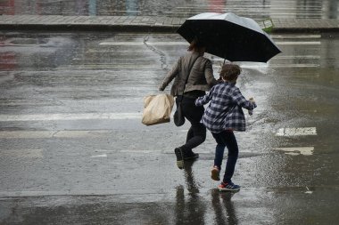 Bucharest, Romania - June 18, 2021: People cross the street on the run in Unirii Square, during heavy rain, in Bucharest, Romania. This image is for editorial use only.