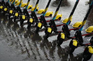 Bükreş, Romanya - 18 Haziran 2021: Bükreş 'teki yoğun yağmurda kaldırıma elektrikli scooterlar park edildi. Bu resim sadece editörler içindir..