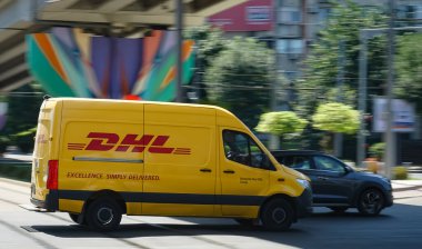 Bükreş, Romanya - 11 Ağustos 2021 Bükreş 'te trafikten hızla geçen sarı bir DHL teslimatı. Bu resim sadece editörler içindir..