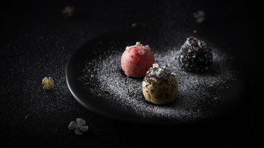 Üç çeşit yer mantarı, biri pembe, biri siyah, biri bej, üzerine toz serpiştirilmiş..