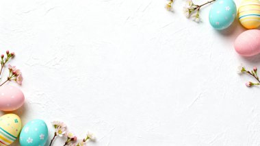 Kiraz çiçekleri ve pastel Paskalya yumurtaları beyaz desenli taş arka planda sanatsal olarak düzenlenir..