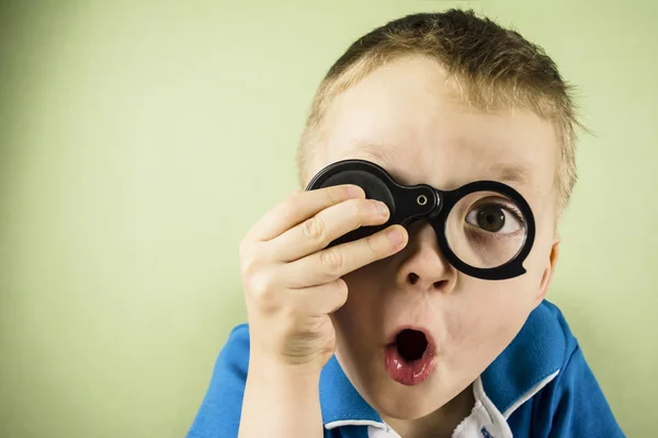 Boy looking through a magnifying glass — Stock Photo, Image