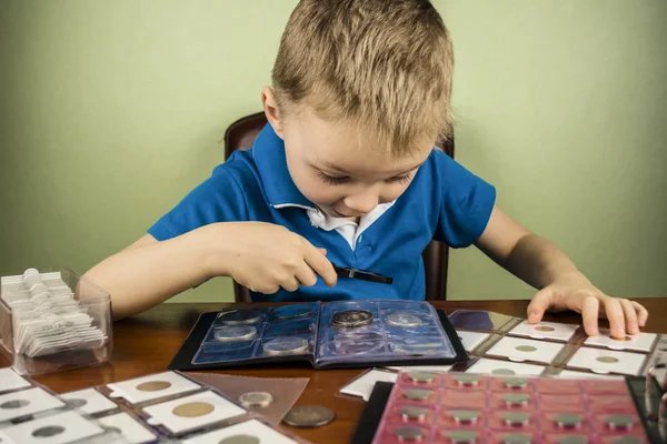 Chłopiec widzi monety przez szkło powiększające Obrazek Stockowy