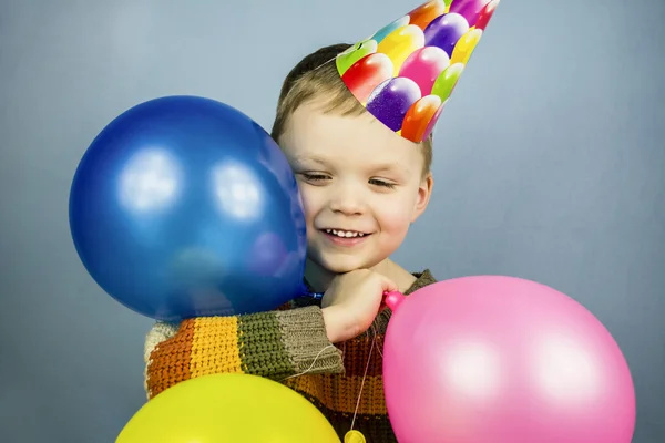 A fiú egy ünnepi kap gazdaság színes léggömbök — Stock Fotó