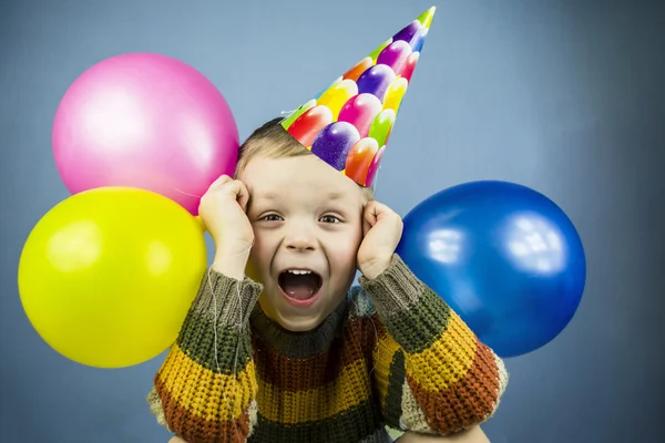 A fiú egy ünnepi kap gazdaság színes léggömbök — Stock Fotó