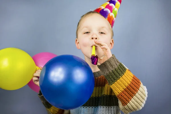 Boy in a celebratory cap holding colorful balloons — Stock Photo, Image