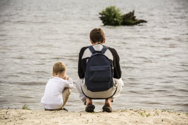 Nehir kıyısında oturan çocuklar