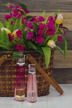 Parfüm ve güzel bir buket çiçek, kırmızı gül ve ahşap sepetteki laleler.