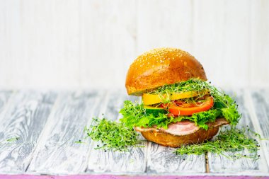Domuz yağı ve etle iştah açıcı hamburger, sarı biber, sebze ve salata ahşap arka planda. 