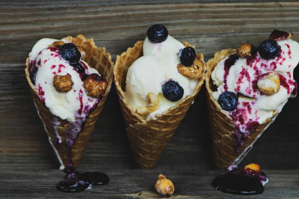 古い木の背景にあるワッフルグラスにブルーベリークリームとナッツの白いアイスクリーム — ストック写真