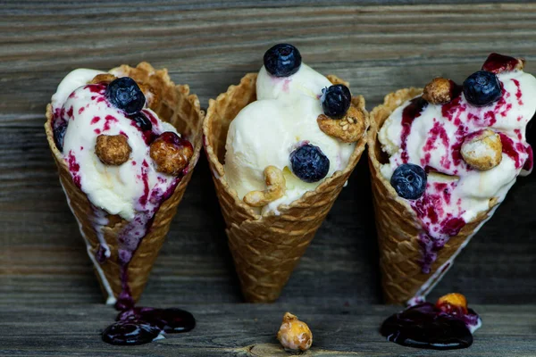 白色冰淇淋 蓝莓奶油和坚果在一个旧木制背景的华夫饼干杯 — 图库照片