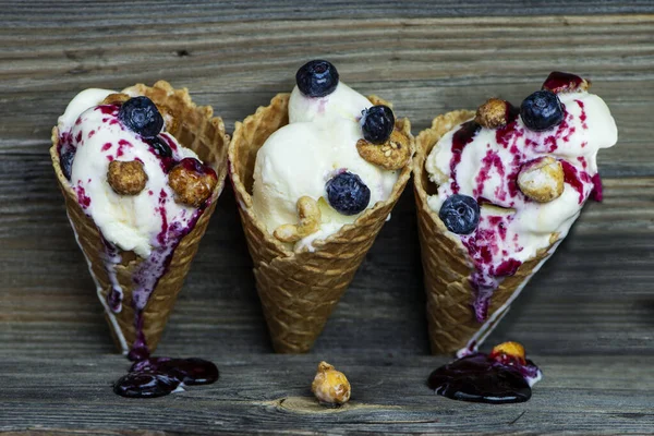 white ice cream with blueberry cream and nuts in a waffle glass on an old wooden background