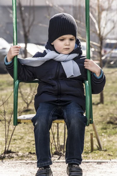 Sad little boy on a swing — Stock Photo, Image