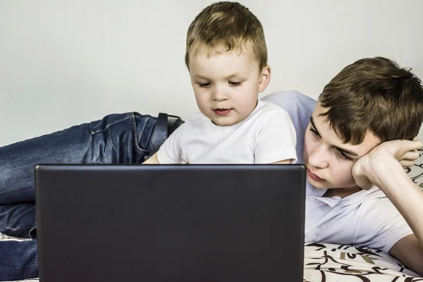 Irmãos, uma criança e um adolescente para laptop — Fotografia de Stock