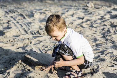 Yaz aylarında sahilde kum bir çocuk oynar