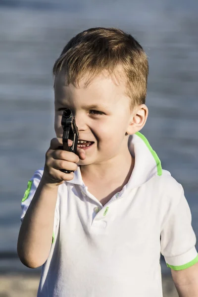Kluk střílí hračku pistoli v létě na pláži — Stock fotografie