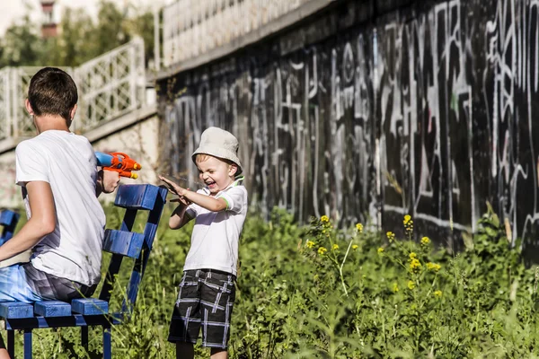 Menino e adolescente jogando pistola de água de verão na rua — Fotografia de Stock