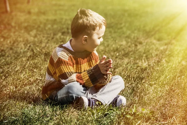 Boy sitting on green grass — Stock Photo, Image