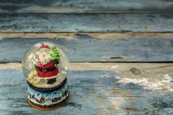 Glaskula med jultomten på en planka — Stockfoto