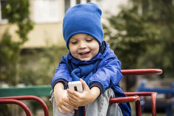 Мальчик на улице играет в телефон — стоковое фото