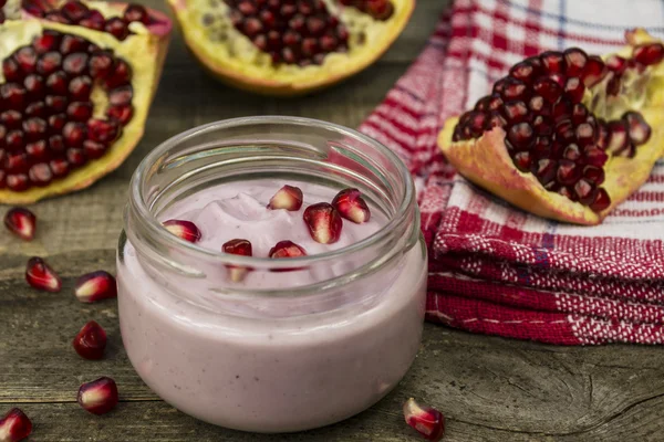 Granaatappel yoghurt en granaatappel zaden op een tafel — Stockfoto