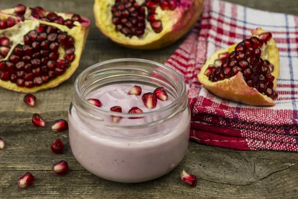 Granaatappel yoghurt en granaatappel zaden op een tafel — Stockfoto