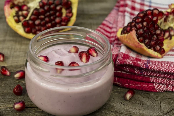 Granaatappel yoghurt en granaatappel zaden op een tafel — Stockfoto