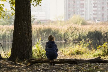 çocuk oturur ve bir günlük bir şehir parkı göle yakın olduğunu düşünüyor