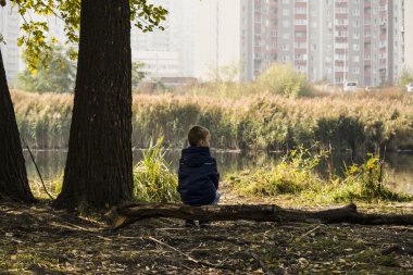 çocuk oturur ve bir günlük bir şehir parkı göle yakın olduğunu düşünüyor