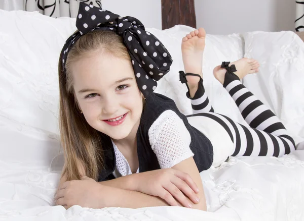 Smiling little girl lying on the couch — Stock Photo, Image