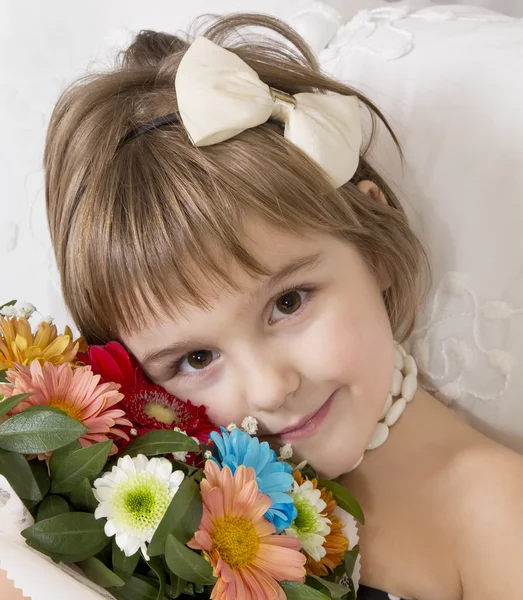 Hermosa niña sonriendo sosteniendo flores de colores brillantes — Foto de Stock