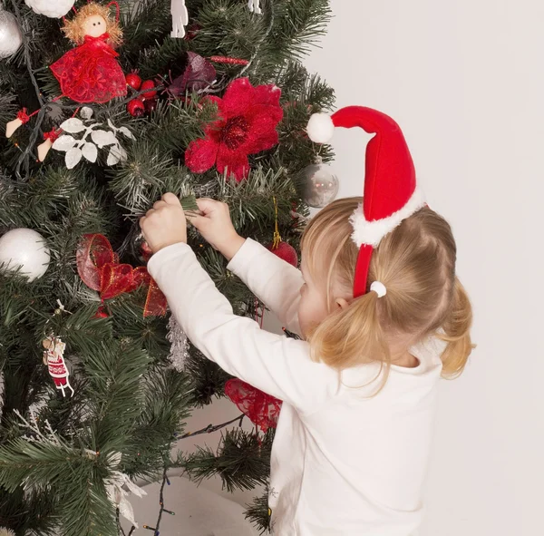 Chica cuelga en un árbol de Navidad juguetes — Foto de Stock