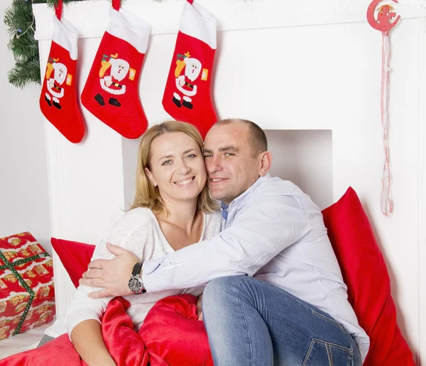 คู่รักนั่งใกล้กับเตาผิงคริสต์มาส — ภาพถ่ายสต็อก