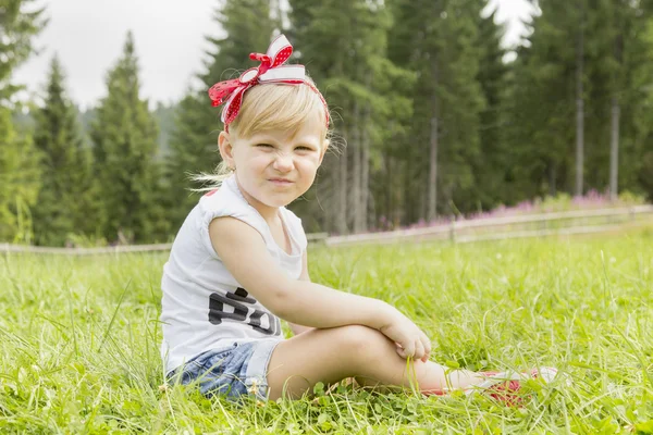 Menina bonita sentada no prado — Fotografia de Stock