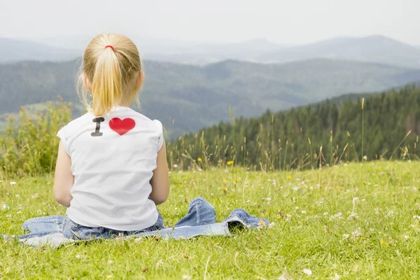 Flicka sitter på en bergstopp — Stockfoto