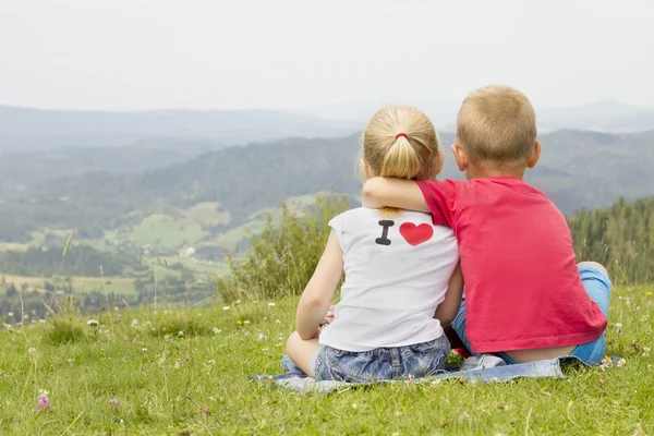 Meisje en jongen zittend op een berg — Stockfoto