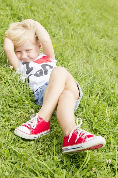 Klein meisje liggen op het gras en dromen — Stockfoto