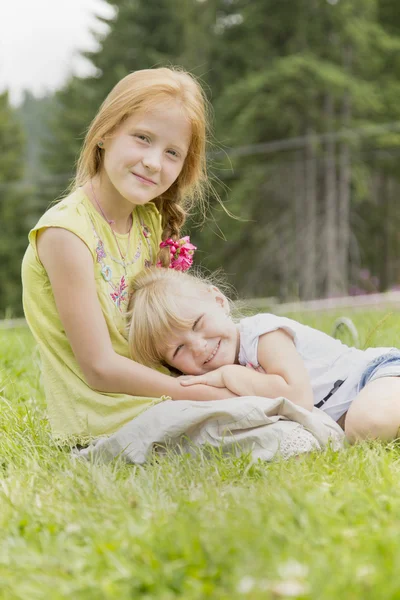 Sisters sitting on the meadow — Stock Photo, Image