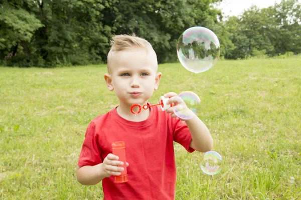 Menino infla um balão andando no parque — Fotografia de Stock