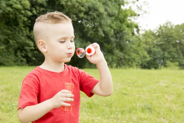 Jongen opgeblazen een ballon wandelen in het park — Stockfoto