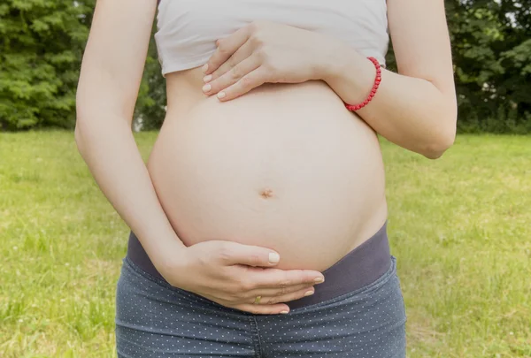 Gravid kvinna omfamnar hennes mage — Stockfoto