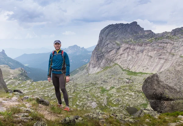 Muž na vrcholu kopce sleduje nádherné scenérie v horách v létě — Stock fotografie