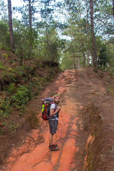 Joven con una mochila naranja va sendero de montaña — Foto de Stock