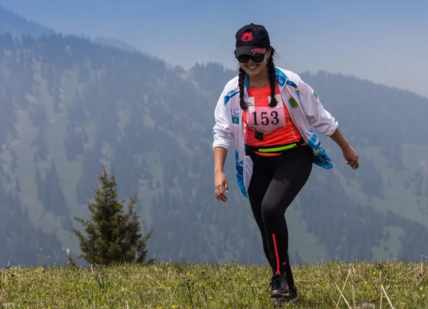 ALMATY, ALMATY DISTRIKT, KAZAKHSTAN - 22 DE MAYO DE 2016: Competencia abierta SKY RANNING 2016 celebrada en el desfiladero de Eliksay. Una chica corre hasta la montaña llamada Bukreeva participando en la competencia — Foto de Stock