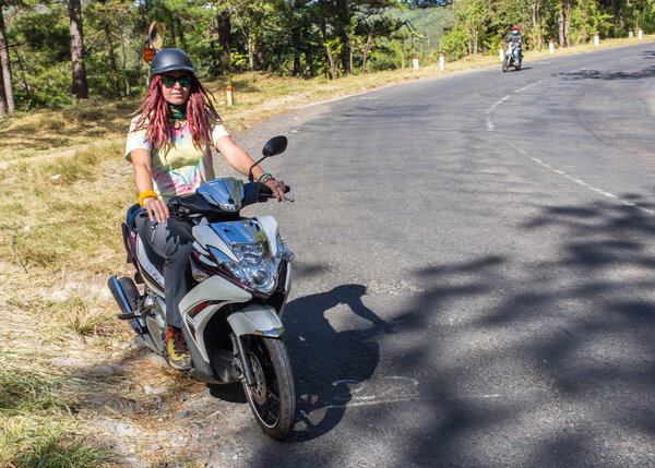 Young woman driving a scooter at the beach