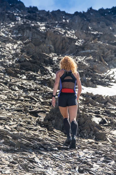 Female running in mountains under sunlight.