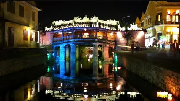 Les couples traversent un pont décoré de lanternes rouges la nuit — Video