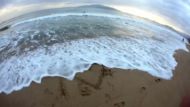 Inskriptionen "love" på sand tvättar våg — Stockvideo