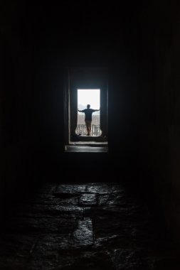 boş iç tarafından dramatik güneş ışığı yaktı penceresinde, bakan erkek siluet.